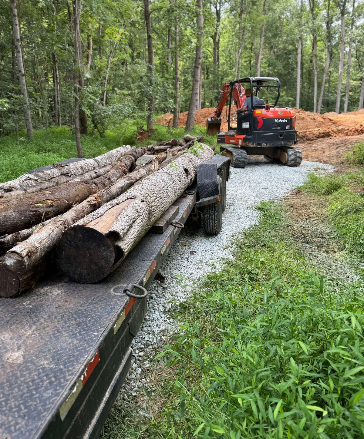 Loaded trailer with logs and equipment at a local work site